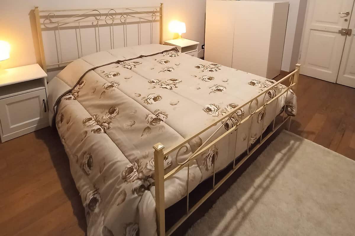 A bedroom with a bed, bedside tables, a wardrobe, and a carpeted floor.