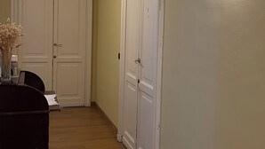 Un pasillo con suelo de madera, un aparador de madera oscura y dos puertas blancas.