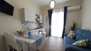 Una cocina moderna con armarios blancos, una mesa de comedor con sillas y un sofá azul con almohadones decorativos.