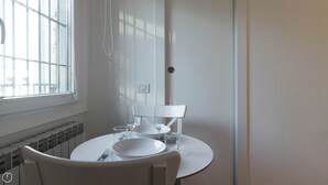 A small dining area with a round table, white chairs, a bowl, a plate, and a glass. - Italianway - Moscova 52 A (Milan)
