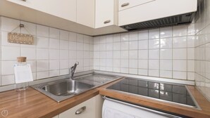 A kitchen with white tiled walls, stainless steel sink, and a built-in stove. - Italianway - Moscova 52 A (Milan)