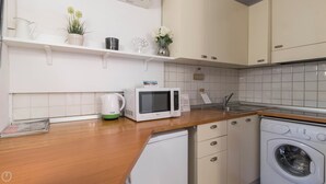 A modern kitchen with white cabinetry, a microwave, a sink, and a washing machine. - Italianway - Moscova 52 A (Milan)
