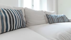 A white sofa with striped pillows and a window in the background. - Italianway Easy - Sarpi 10 A (Milan)