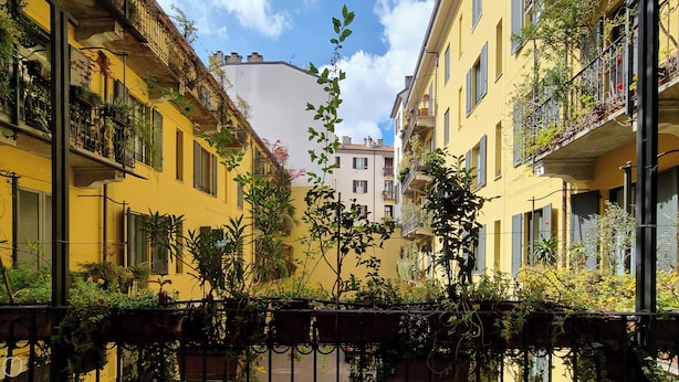 A narrow street with yellow buildings, balconies with plants, and a clear sky. - Italianway Easy - Sarpi 10 A (Milan)