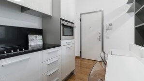 A modern kitchen with white cabinets, a black countertop, and a built-in oven. - Italianway Easy - Sarpi 10 A (Milan)