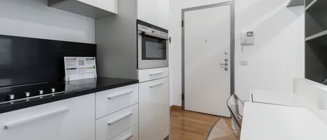 Una cocina moderna con armarios blancos, encimera negra y horno empotrado.