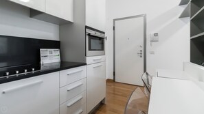 A modern kitchen with white cabinets, a black countertop, and a built-in oven. - Italianway Easy - Sarpi 10 A (Milan)