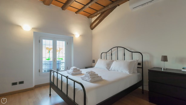 Une chambre à coucher avec un lit, une table de chevet, une lampe et une fenêtre donnant sur un beau paysage.