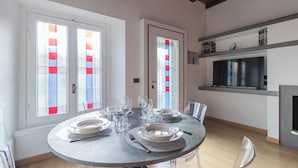 Un coin repas avec une table ronde dressée pour quatre personnes, agrémentée d’assiettes, de verres et de couverts.
