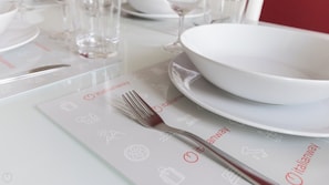 A table set with a white placemat featuring icons, a white bowl, and a fork. - Italianway Comfort - Borsieri 11 B (Milan)