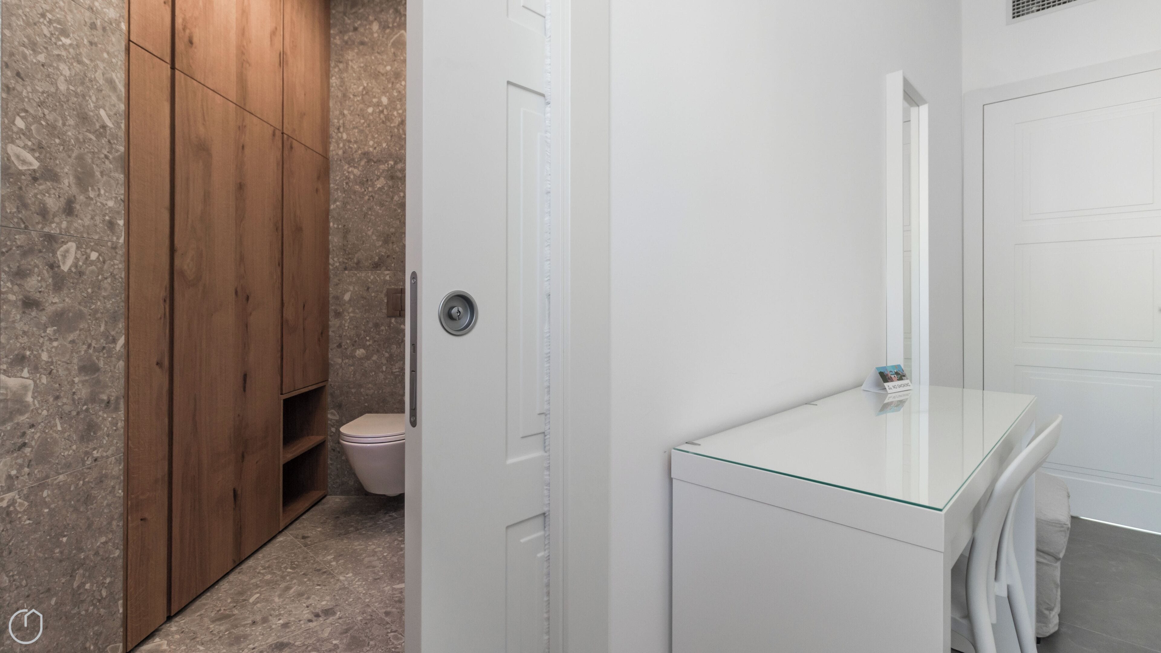 A bathroom with a wooden cabinet, a toilet, and a glass shower enclosure.