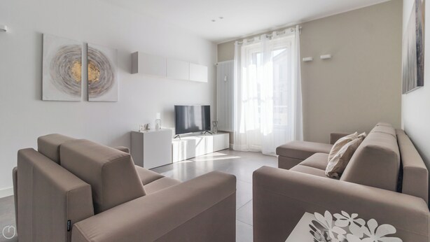 Een moderne woonkamer met een zithoek, een televisie en kunst aan de muur.