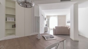 Een moderne keuken met een houten tafel, witte stoelen en een inbouwboekenplank.