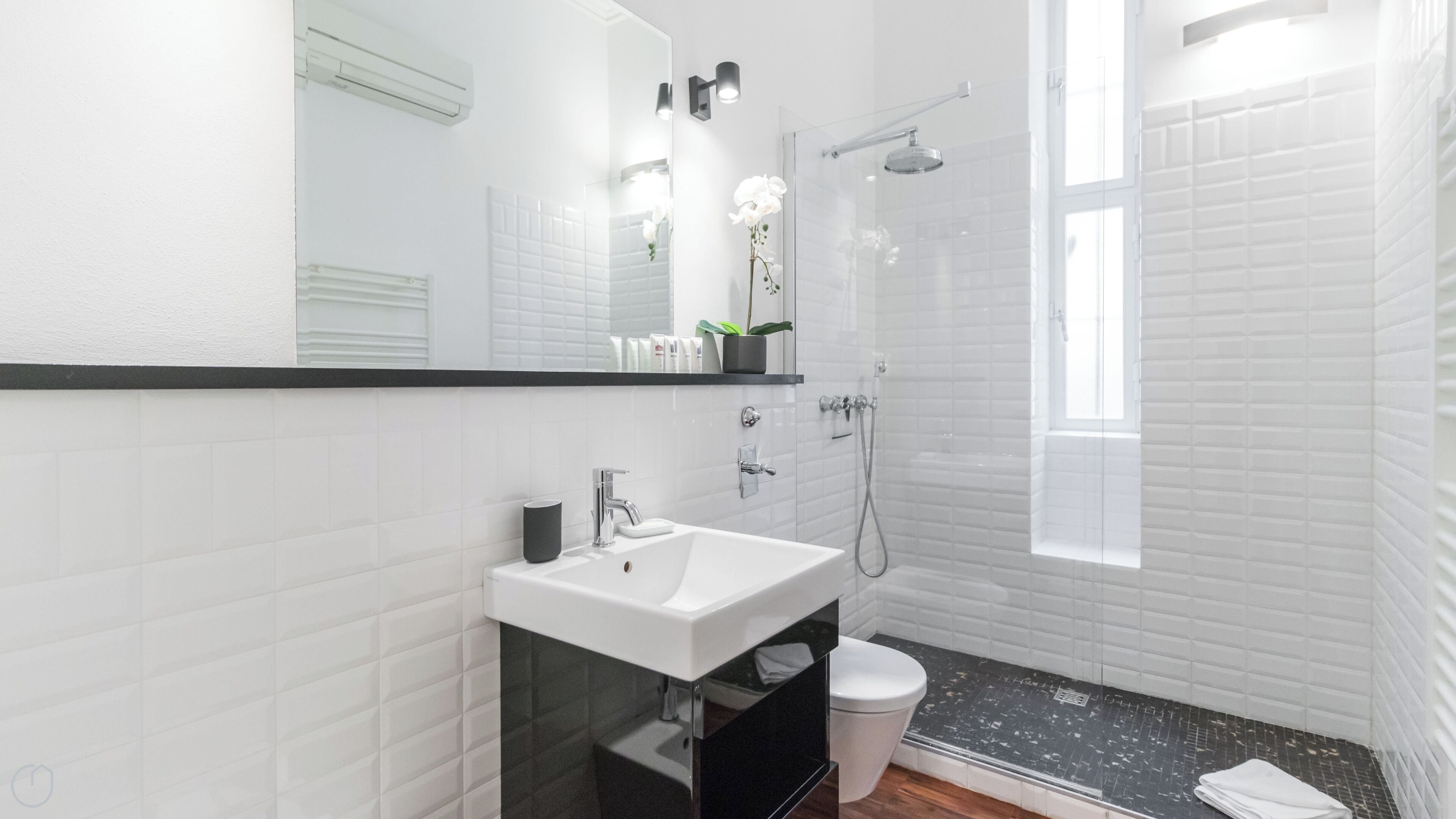 A modern bathroom with a white sink, mirror, and shower.