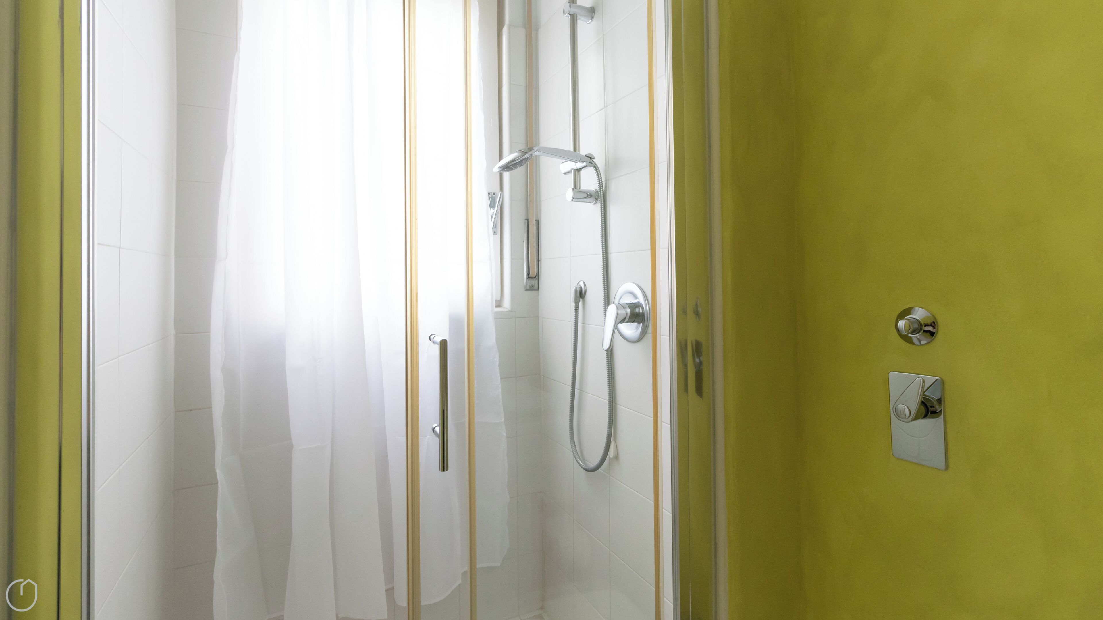 A shower with a handheld showerhead and a wall-mounted faucet.