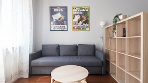 A living room with a grey sofa, a round wooden table, and a bookshelf. - Italianway Easy - Sanfelice 10 (Milan)