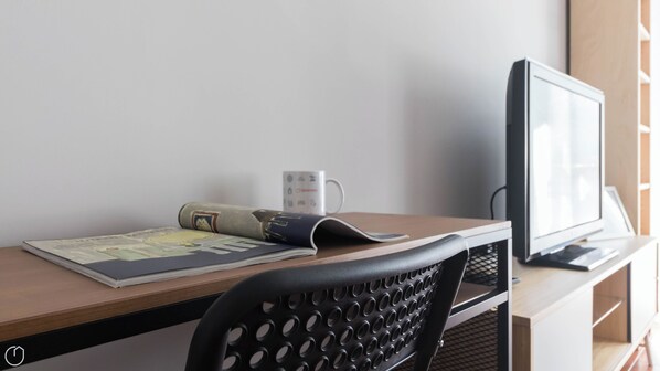 A desk with a computer monitor, a keyboard, a mouse, a mug, and a rolled-up magazine. - Italianway Easy - Sanfelice 10 (Milan)