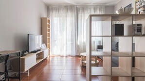 A modern living room with a flat-screen TV, a desk with a computer, and a bookshelf. - Italianway Easy - Sanfelice 10 (Milan)