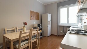 A compact kitchen with a dining table, chairs, a microwave, a refrigerator, and a gas stove. - Italianway Easy - Sanfelice 10 (Milan)
