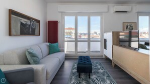 A modern living room with a sofa, a coffee table, and a view of the city through large windows. - Italianway - Boiardo 27 (Milan)