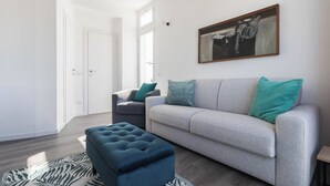 A modern living room with a grey sofa, teal cushions, a blue ottoman, and a zebra-patterned rug. - Italianway - Boiardo 27 (Milan)