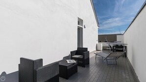 A rooftop terrace with black wicker furniture, a small table, and a chair. - Italianway - Boiardo 27 (Milan)