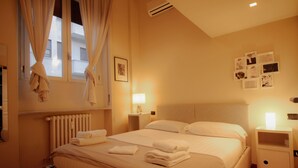 Ein Hotelzimmer mit einem Bett, Nachttischen, einem Heizkörper und einer Wand mit Bildern.