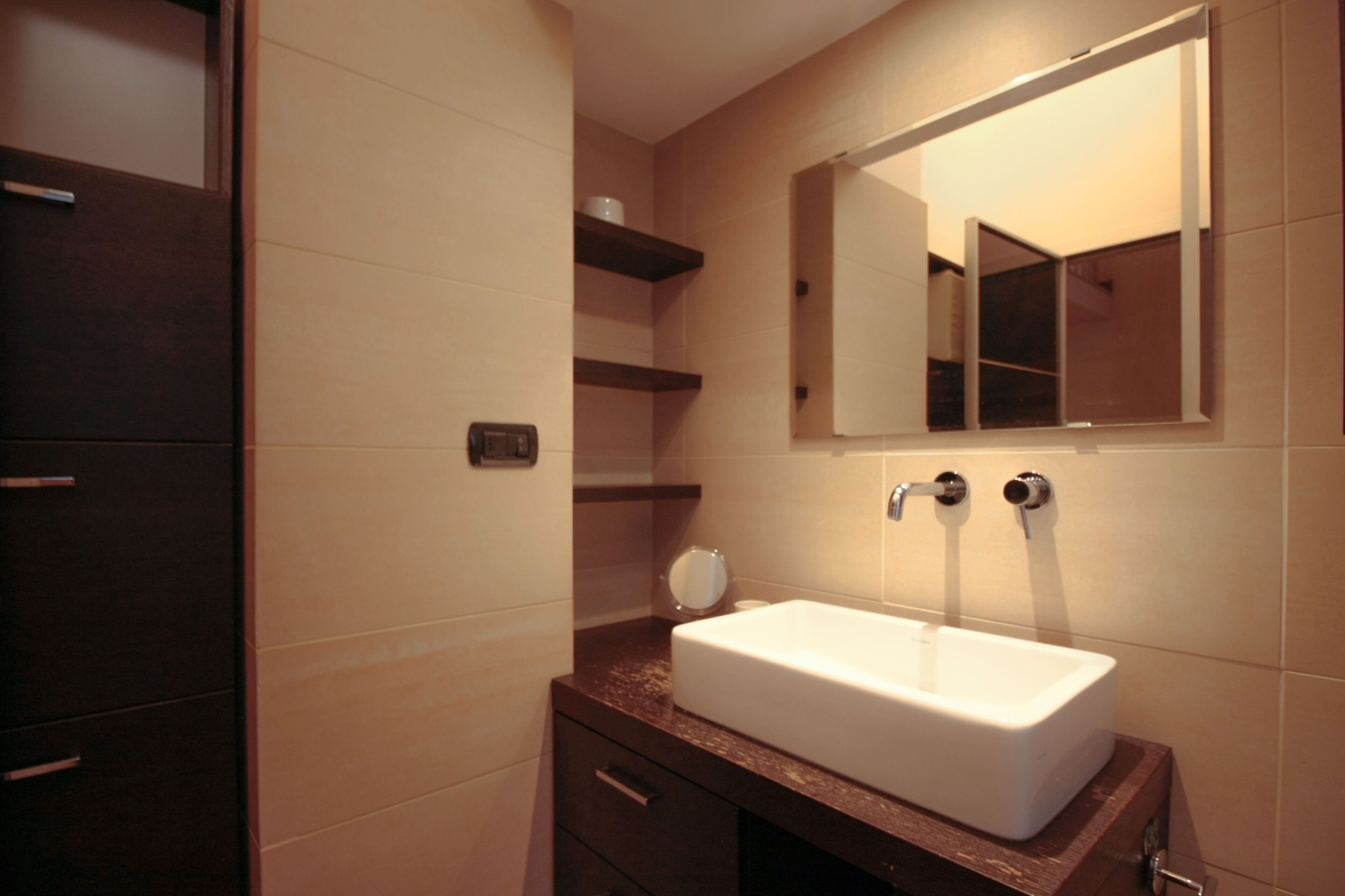 A bathroom with a white sink, a mirror, and a wooden vanity.