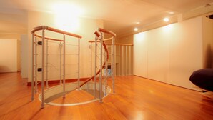 Ein geräumiger Raum mit Holzboden, einem Rundtrainingsbereich und einer Treppe.