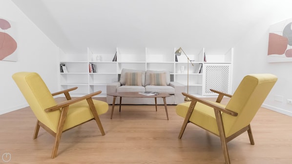 A modern living room with a sofa, two yellow armchairs, a coffee table, and white shelving units.