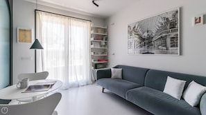 Uma sala de estar moderna com um sofá cinza, uma mesa de centro redonda e uma estante.