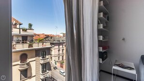 Une pièce avec vue sur la ville, visible à travers une fenêtre ornée de rideaux blancs.