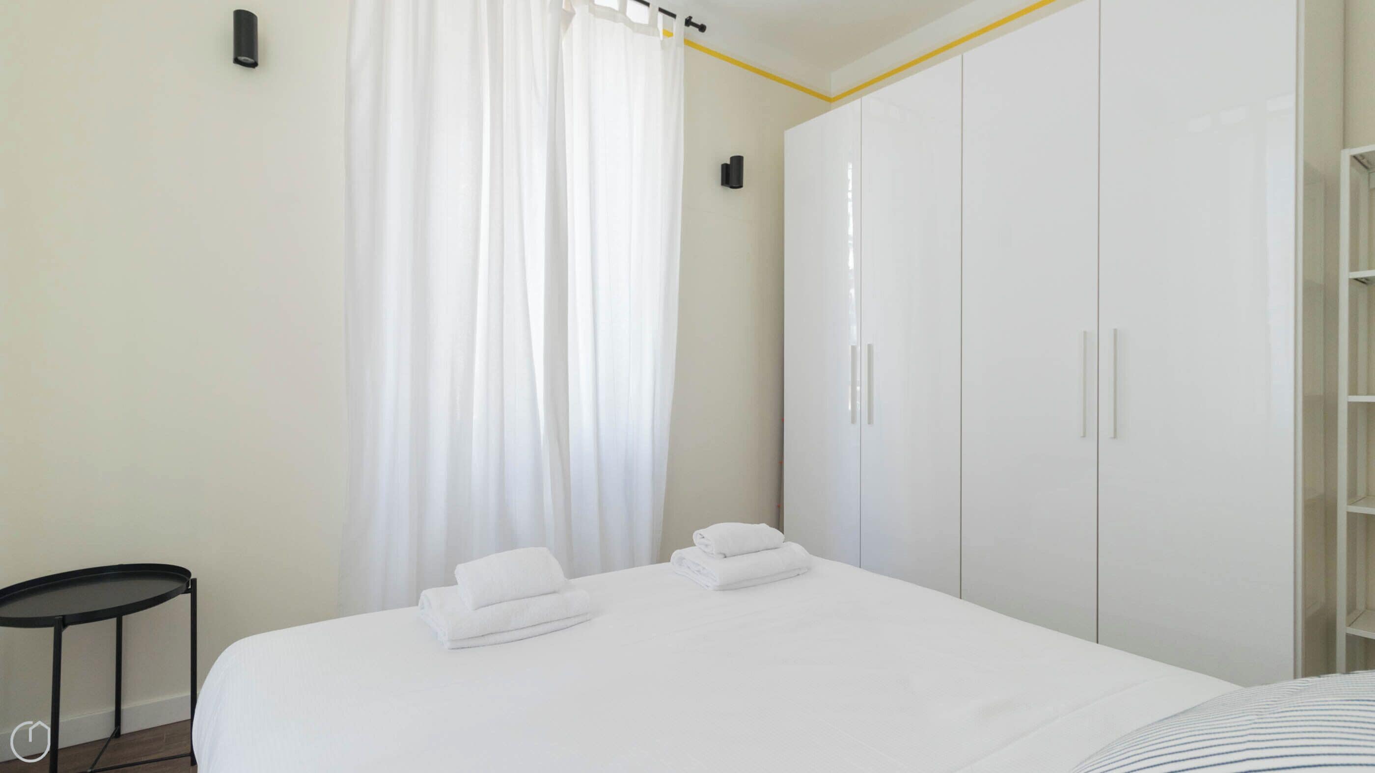 Una habitación de hotel con cama, una mesita y un armario.