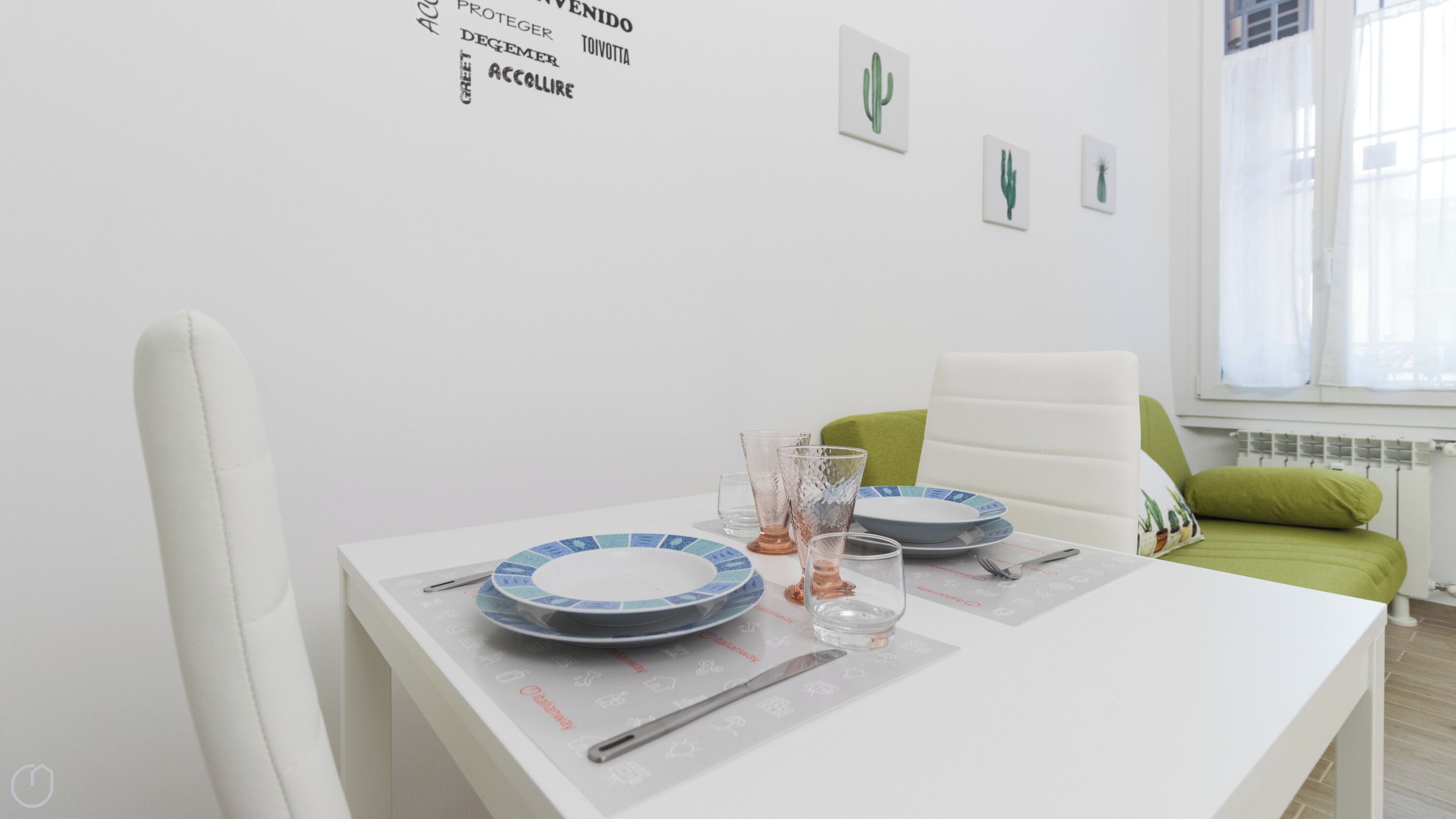 A dining table set with plates, glasses, and cutlery, a white chair, and a green cushion.