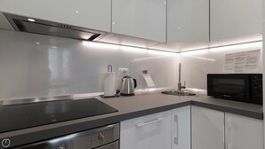 A modern kitchen with a black induction cooktop, stainless steel appliances, and a sink with a faucet.