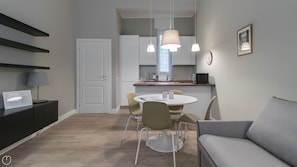 A modern kitchen with white cabinets, a dining table with chairs, and pendant lights.