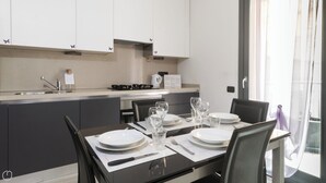 A modern kitchen with grey cabinets, a dining table set for four, and a view of the outside through a large window.