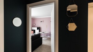 A hallway leading to a living area with a round mirror, a hexagonal mirror, and a black couch. - Italianway Comfort - Buenos Aires 65 A (Milan)