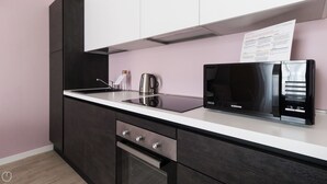 A modern kitchen with a black microwave, stainless steel appliances, and a white countertop. - Italianway Comfort - Buenos Aires 65 A (Milan)