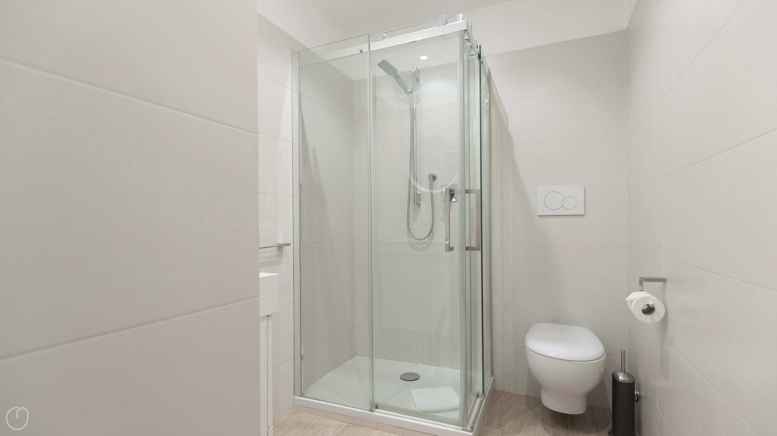 A modern bathroom with a glass-enclosed shower, a toilet, and a towel rack.