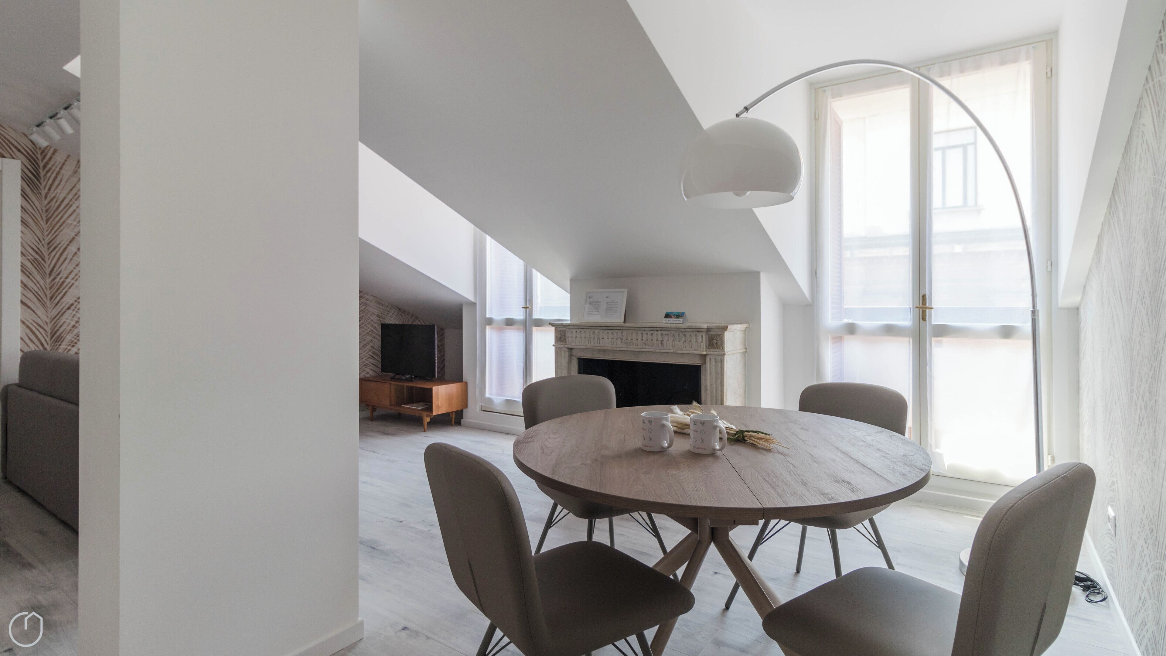 Uma sala de estar moderna com uma mesa redonda de madeira, seis cadeiras, uma lareira e uma janela ampla.