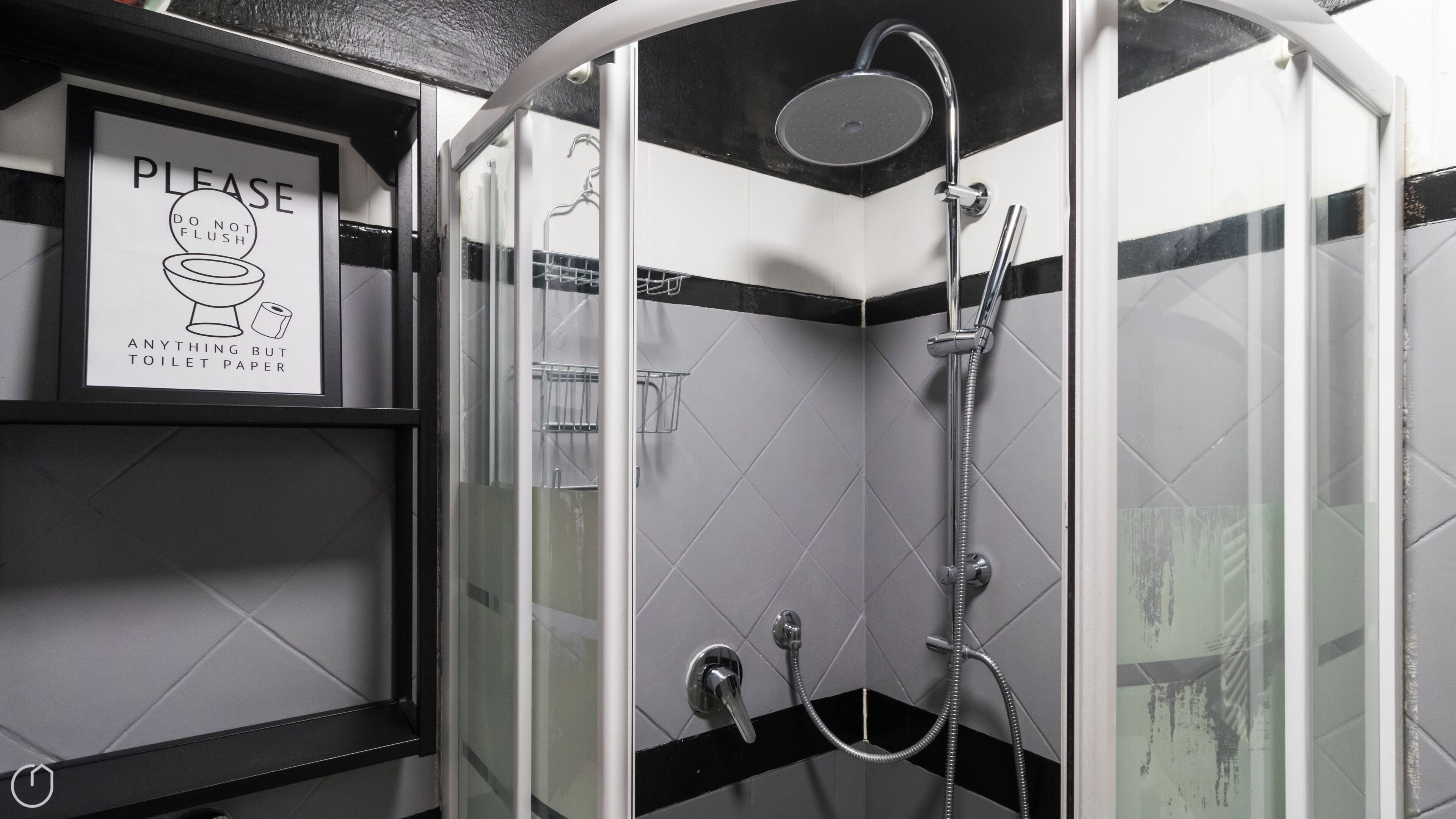 A bathroom with a shower, a toilet paper dispenser, and a sign instructing not to flush anything but toilet paper.