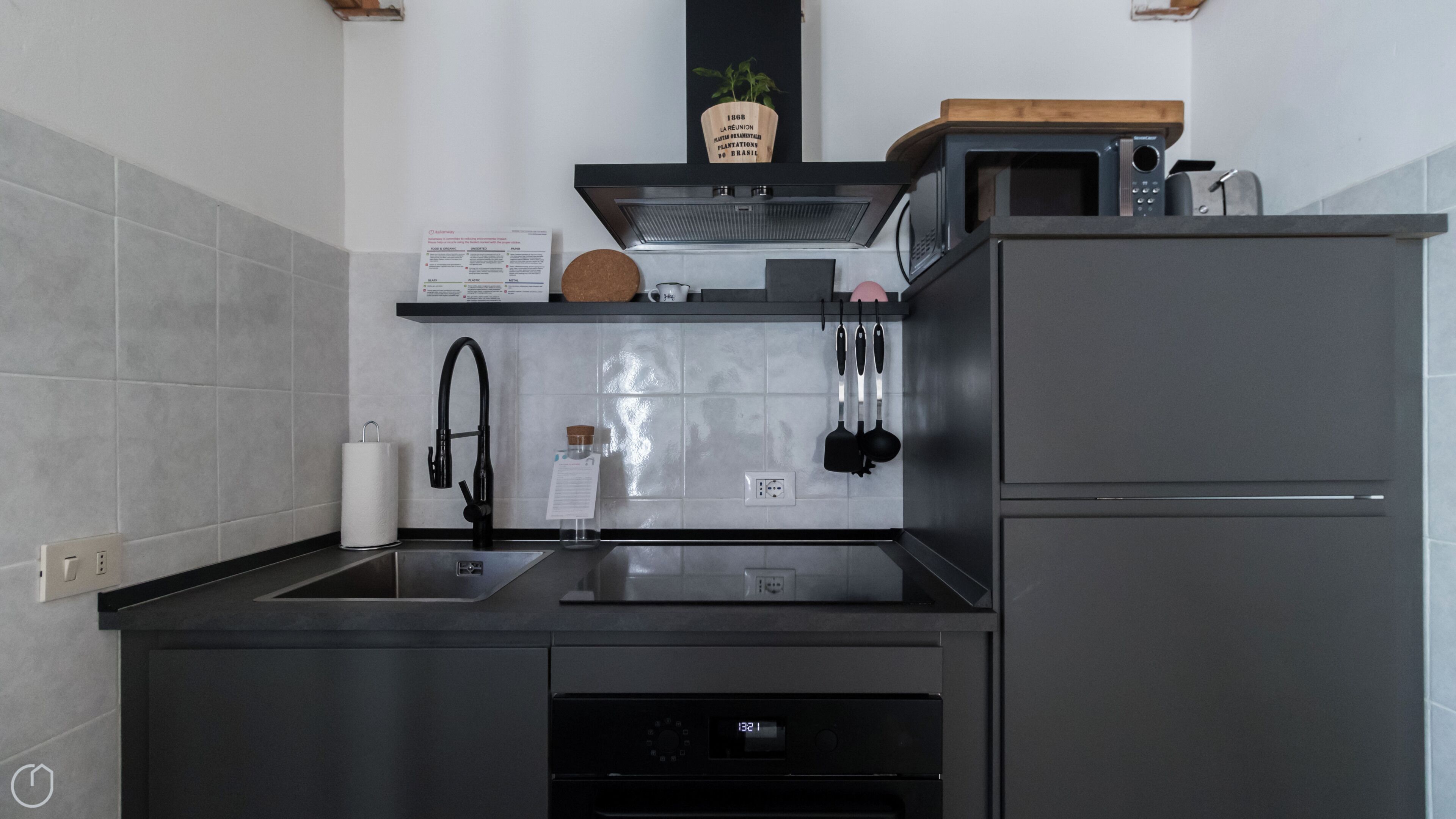 A modern kitchen with a stainless steel sink, a built-in oven, and a microwave on the countertop.