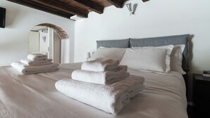 Ein ordentlich gemachtes Bett mit gefalteten Handtüchern und einem grauen Kopfteil.