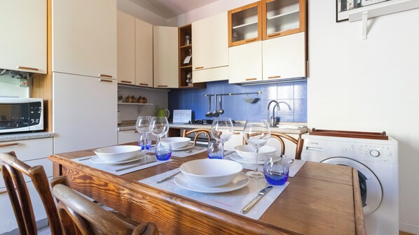 A compact kitchen with white cabinets, a microwave, and a washing machine.