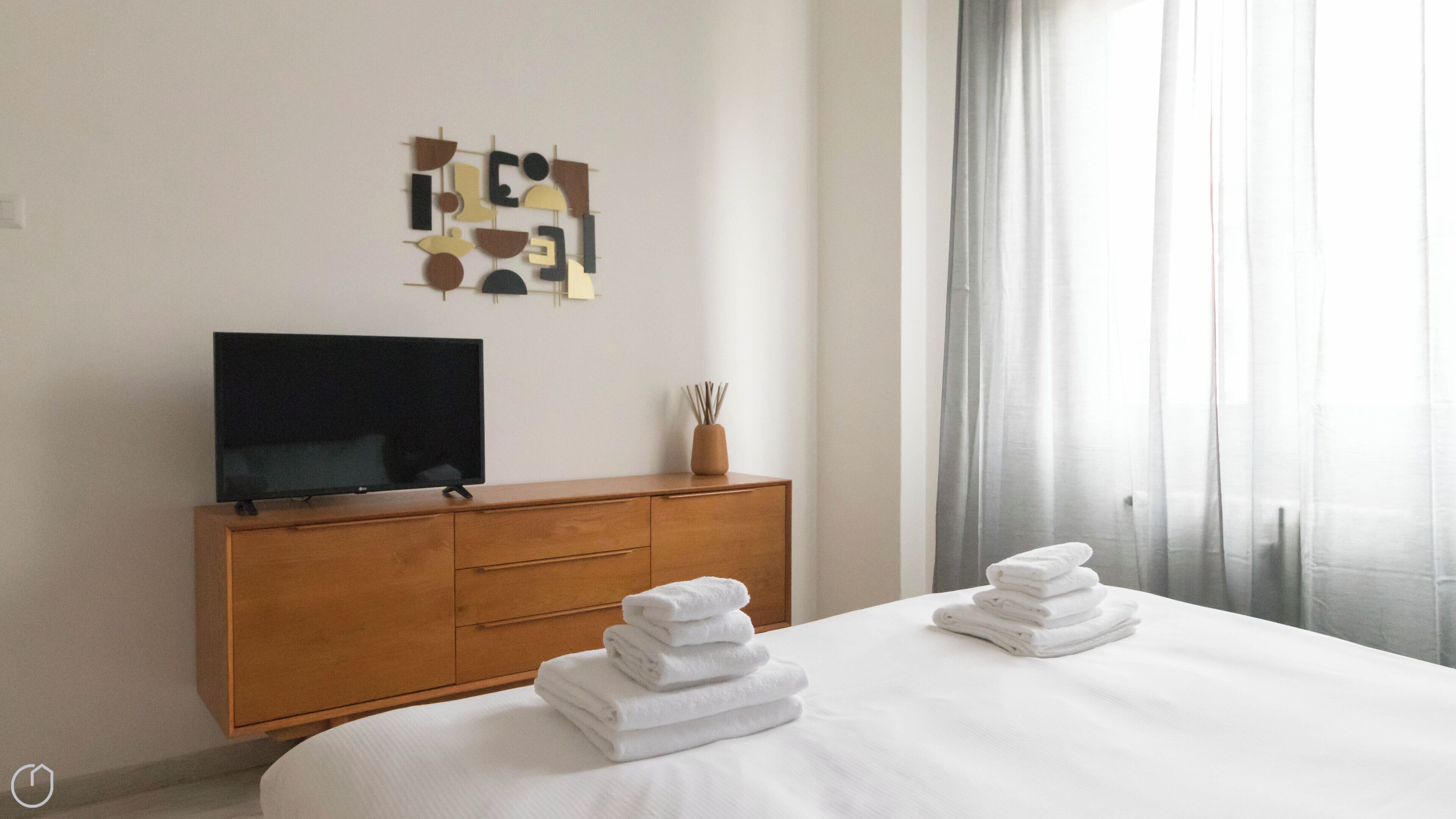 Ein Hotelzimmer mit einem Bett, einem Holzschrank, einem Flachbildfernseher und einem Wandbild.
