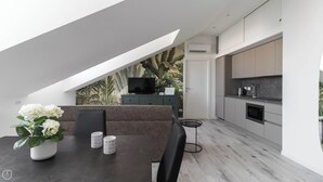 A modern kitchen with a built-in oven and a dining area with a dark wood table and a sofa. - Italianway - Commenda 35 C (Milan)