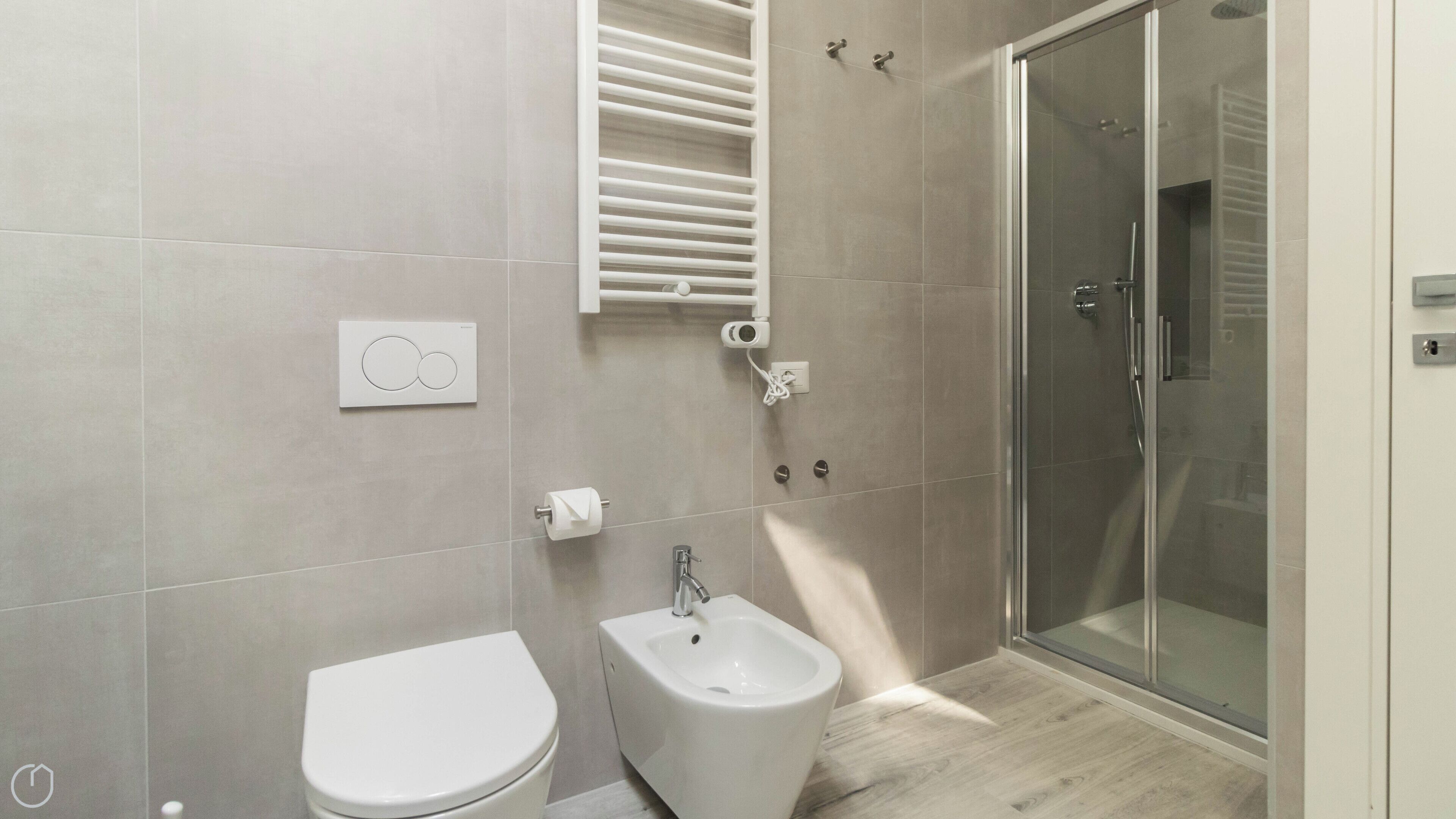 A modern bathroom with a toilet, bidet, and glass shower enclosure.