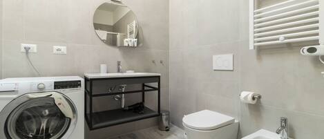 Un bagno moderno con lavatrice, lavandino, WC e specchio.