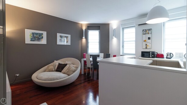 Uma sala de estar moderna com um espaço de estar circular, uma mesa de jantar com cadeiras e uma cozinha com micro-ondas e chaleira.